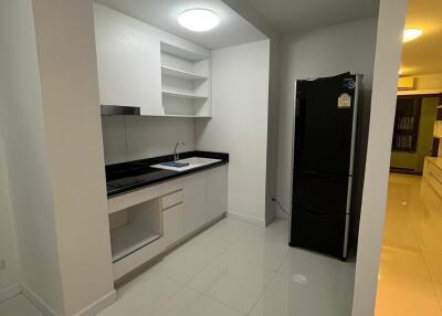 Modern kitchen with sleek white cabinets, black countertop, and a black refrigerator