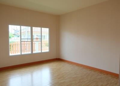 Empty bedroom with large window and wooden floor