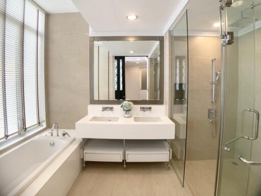 Modern bathroom with large mirror, bathtub, double sink, and glass-enclosed shower