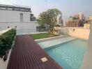 Rooftop pool area with wooden deck and green space