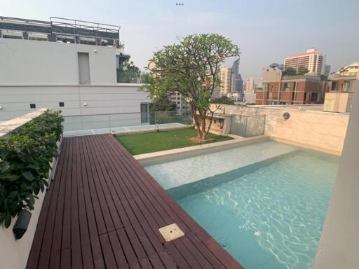 Rooftop pool area with wooden deck and green space