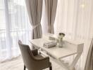 Modern home office setup with white desk and grey chair by large window with curtains