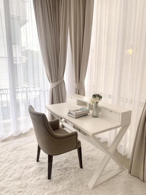 Modern home office setup with white desk and grey chair by large window with curtains