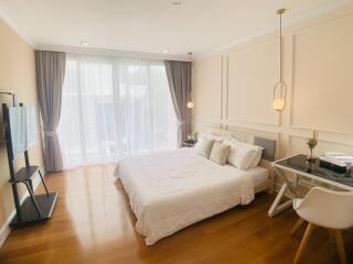 Modern bedroom with a large bed, desk, and large windows.