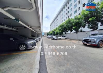 Covered parking area beside a building with several parked cars