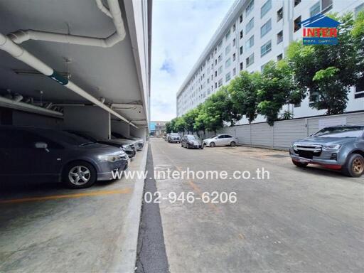 Covered parking area beside a building with several parked cars