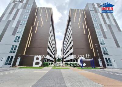 Exterior view of two modern apartment buildings with large letters B and C, part of the complex.