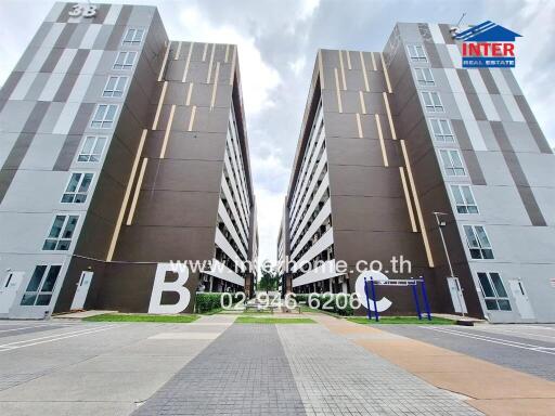 Exterior view of two modern apartment buildings with large letters B and C, part of the complex.