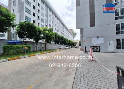 Exterior view of a modern apartment building with pathway and greenery