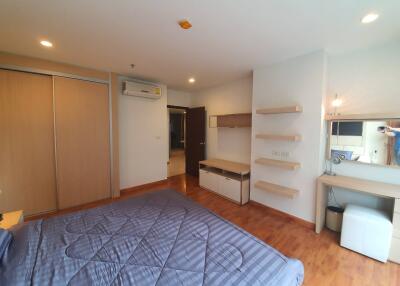 Modern bedroom with wooden floor, bed, built-in closet, air conditioning, and dressing area