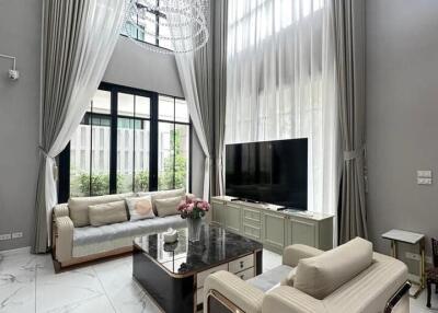 Modern living room with high ceiling, large windows, and contemporary furniture