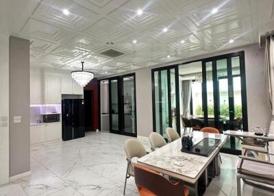 Modern dining area with marble floors and ceiling, a chandelier, glass doors, and garden view