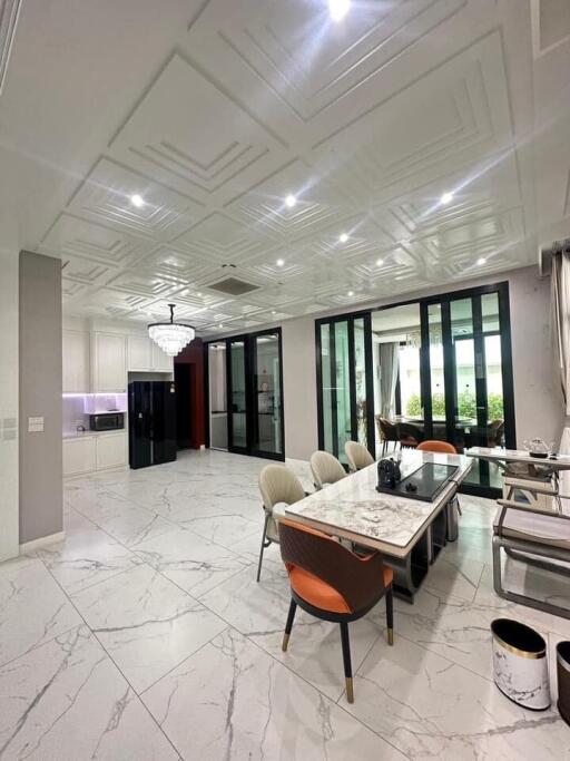 Modern dining area with marble floors and ceiling, a chandelier, glass doors, and garden view