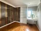 Bedroom with wooden flooring, built-in wardrobe, and vanity area