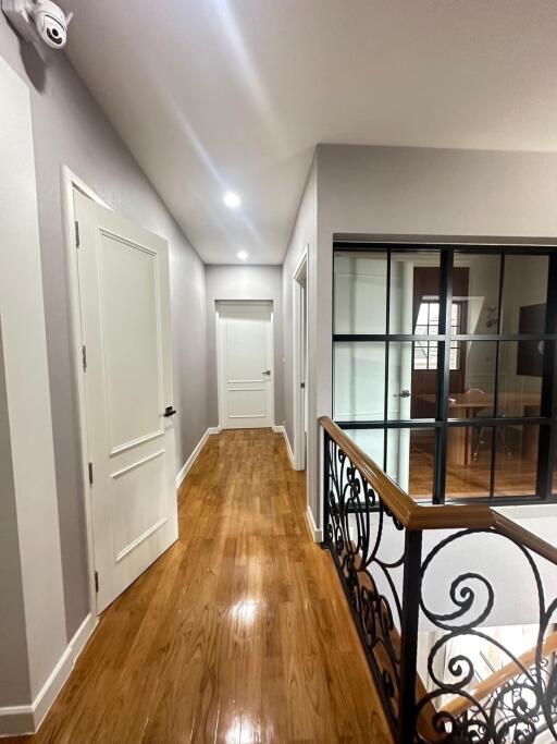 Spacious hallway with natural wood flooring and iron railing