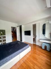 Master bedroom with wooden floor, large mirror, and built-in TV