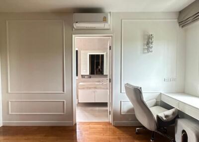 Home office with wooden floors, desk, office chair, and view into an adjacent bathroom