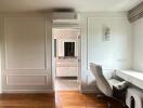 Home office with wooden floors, desk, office chair, and view into an adjacent bathroom