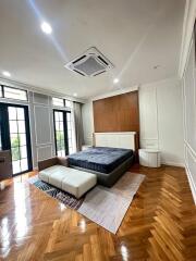 Modern bedroom with wooden flooring, large bed, and natural light