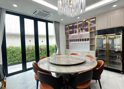 Luxury modern kitchen with a round marble dining table, chandelier, and floor-to-ceiling windows