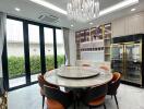 Luxury modern kitchen with a round marble dining table, chandelier, and floor-to-ceiling windows