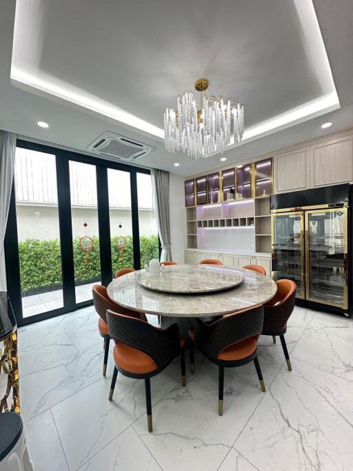 Luxury modern kitchen with a round marble dining table, chandelier, and floor-to-ceiling windows