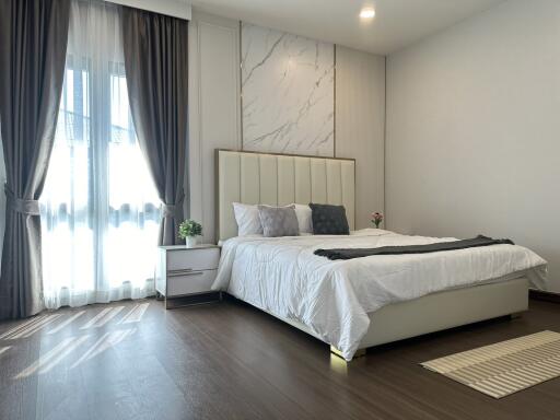 Modern bedroom with large window, curtains, and stylish decor