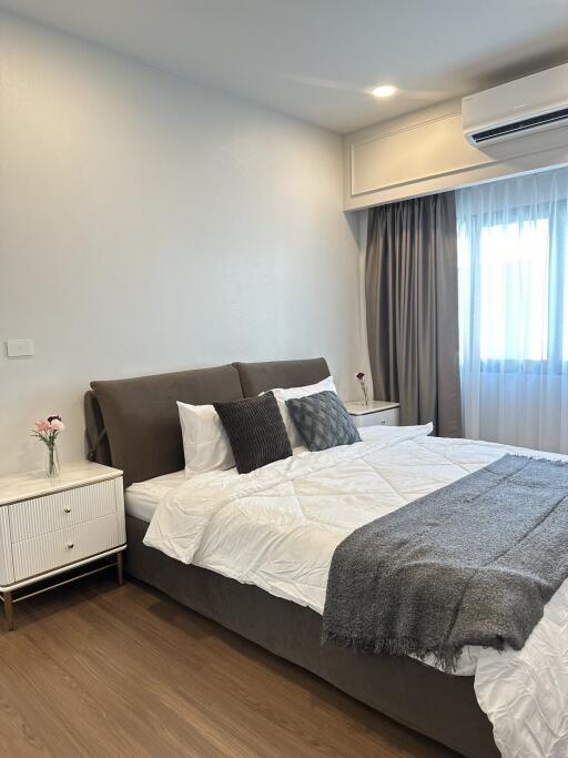 A modern bedroom with a comfortable bed, two nightstands, and an air conditioning unit.