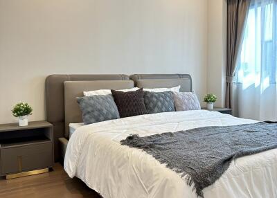 Modern bedroom with a large bed, nightstands, and natural light