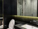 Modern bathroom with dark marble accents, sink, and toilet