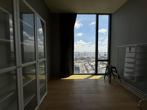 Room with wooden floor, glass cabinets, and a large window with city view