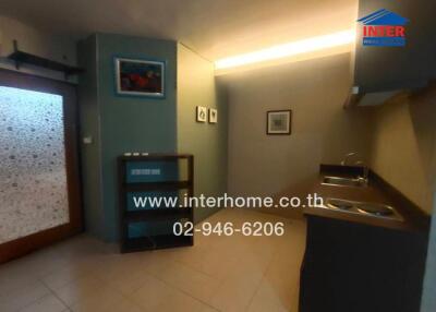 Compact kitchen area with dark countertops and minimalistic shelving