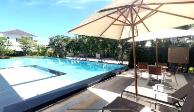 Outdoor pool area with shaded lounge chairs and tables