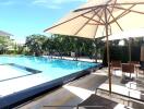 Outdoor pool area with shaded lounge chairs and tables