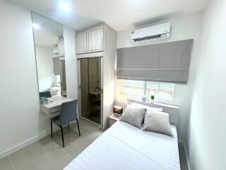 Modern and well-lit bedroom with a double bed, wardrobe, and desk