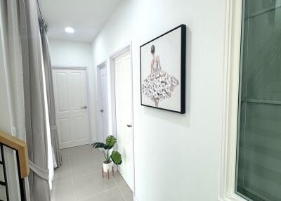 Bright hallway with framed artwork and potted plants