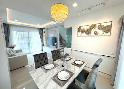 Modern dining and living area with chandelier and natural light