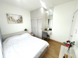 Modern bedroom with white walls, cozy bed, built-in wardrobe, and vanity area