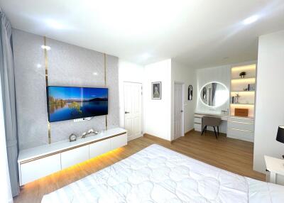 Modern and spacious bedroom with TV, bed, and vanity desk