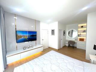 Modern and spacious bedroom with TV, bed, and vanity desk