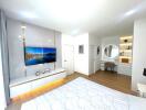 Modern and spacious bedroom with TV, bed, and vanity desk