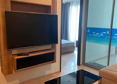 Modern living room with wall-mounted TV and sliding door access to bedroom