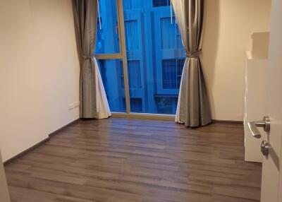 A well-lit bedroom with wooden flooring and large windows