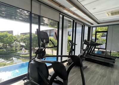 Modern gym with exercise equipment and pool view