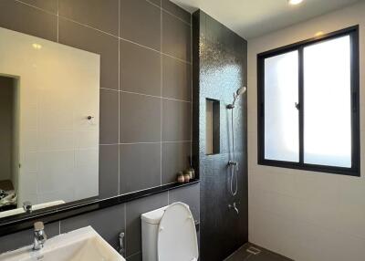 Modern bathroom with toilet, sink, mirror, and shower