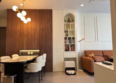 Modern living room and dining area with built-in bookshelves and contemporary lighting