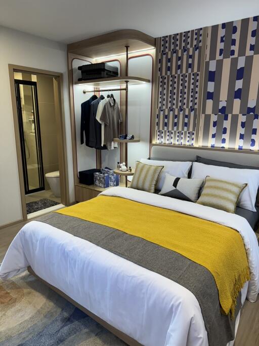 Modern bedroom with wall-mounted wardrobe, decorative bedding, and an en suite bathroom