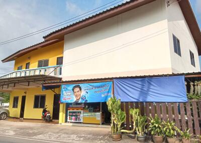 Two-story building with a yellow and white exterior, balcony, and blue awning