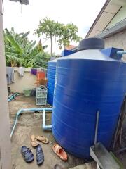 Large blue water storage tanks in an outdoor utility area