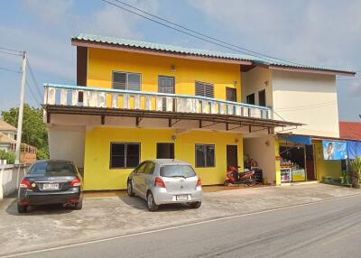 Two-story yellow and white building with parking area and vehicles